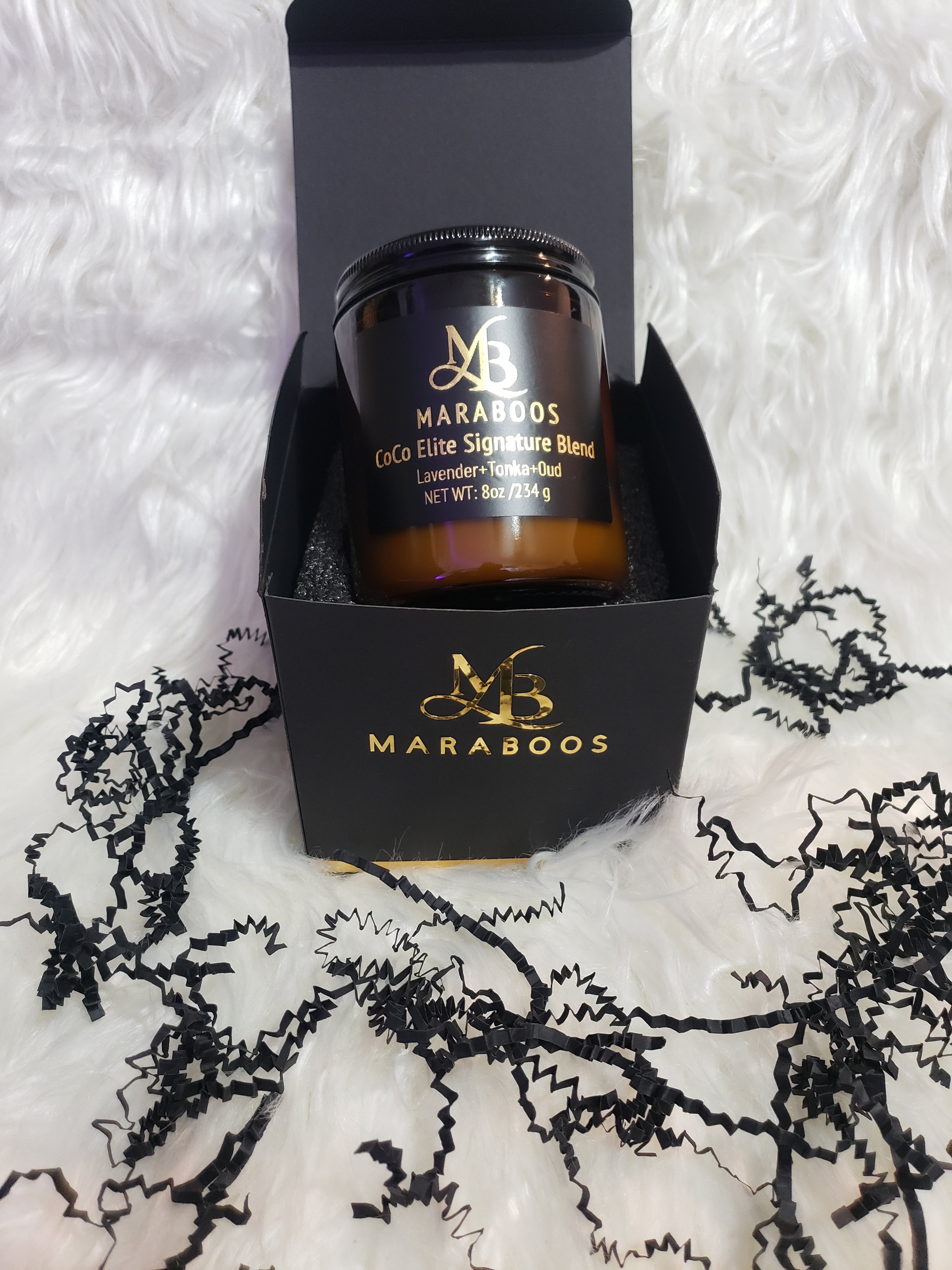 Maraboo's CoCo Elite Signature Blend candle in a black box on a textured white background with black lace.